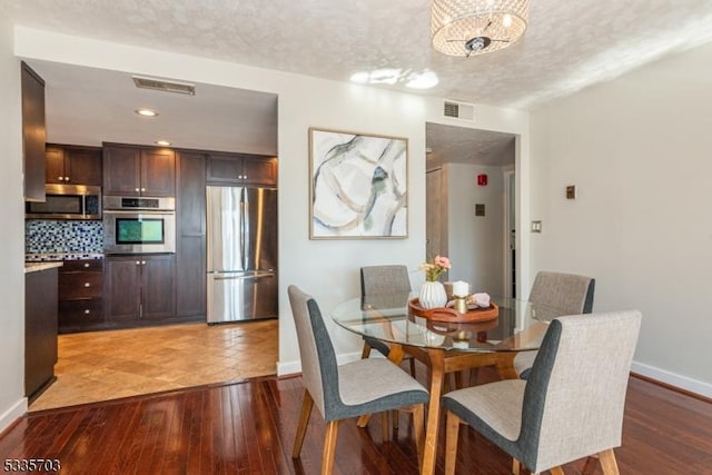 dining space featuring an inviting chandelier, light hardwood / wood-style flooring, and a textured ceiling