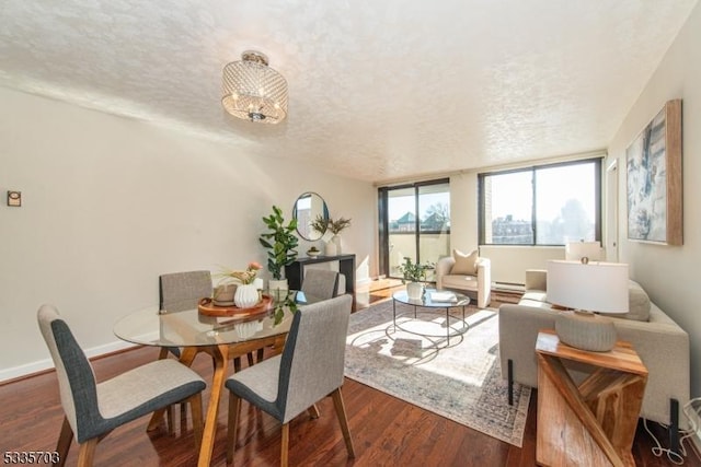 dining area with a baseboard heating unit, hardwood / wood-style flooring, and a textured ceiling