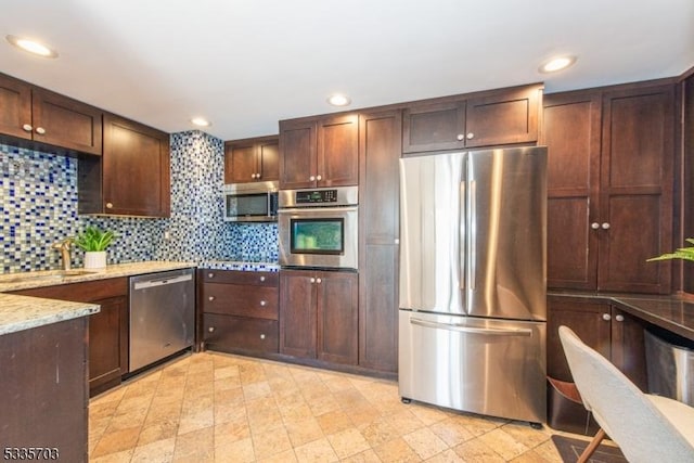 kitchen with stainless steel appliances, light stone countertops, sink, and decorative backsplash