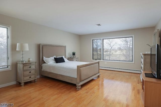 bedroom with a baseboard heating unit and light hardwood / wood-style flooring