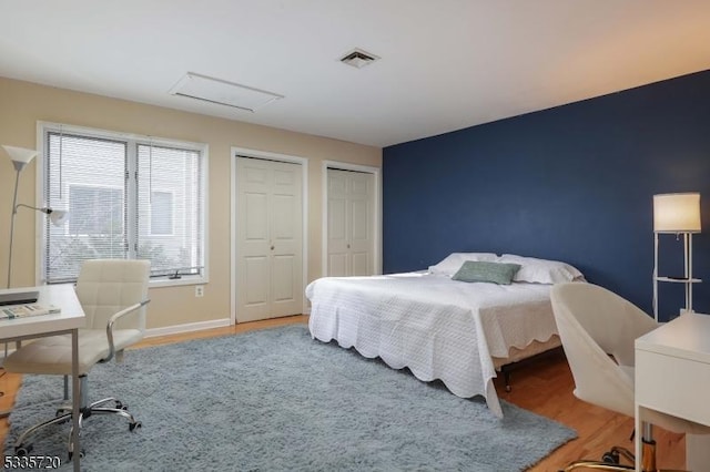 bedroom with multiple closets and hardwood / wood-style floors