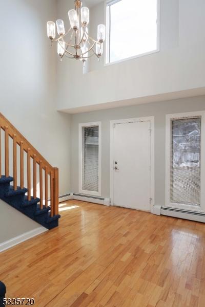 foyer entrance with a chandelier, a towering ceiling, hardwood / wood-style floors, and baseboard heating