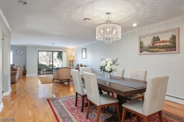 dining space featuring ornamental molding, light hardwood / wood-style floors, and a chandelier