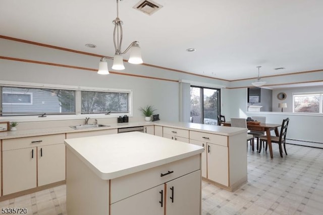 kitchen featuring sink, crown molding, a kitchen island, decorative light fixtures, and kitchen peninsula