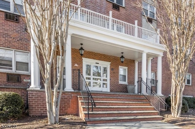 view of exterior entry featuring covered porch and a balcony