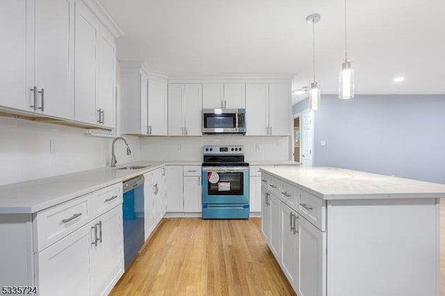 kitchen with sink, white cabinetry, a center island, appliances with stainless steel finishes, and pendant lighting