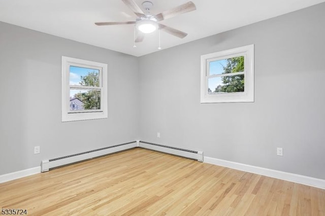 spare room with ceiling fan, a wealth of natural light, light hardwood / wood-style floors, and a baseboard radiator