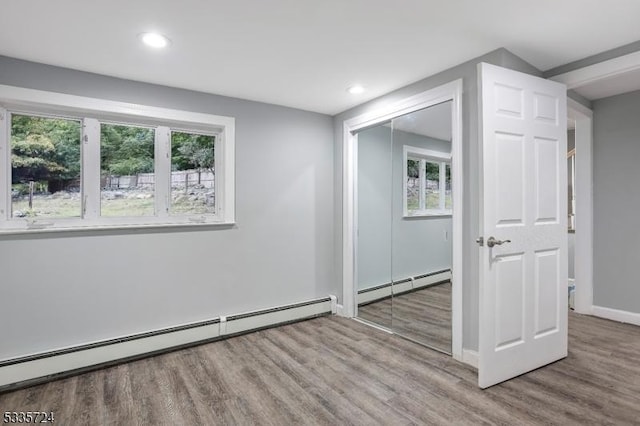 spare room with baseboard heating, a healthy amount of sunlight, and light hardwood / wood-style flooring