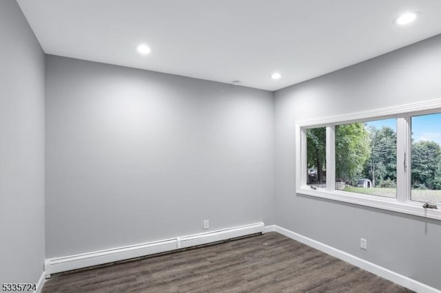 empty room featuring baseboard heating and dark hardwood / wood-style floors