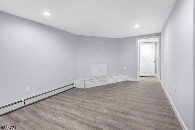 spare room featuring a baseboard heating unit and light hardwood / wood-style flooring