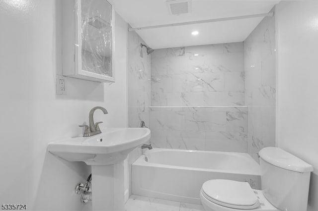 bathroom featuring tiled shower / bath and toilet