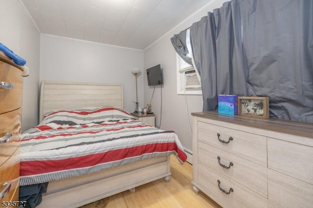 bedroom with crown molding, a baseboard radiator, and light wood-type flooring