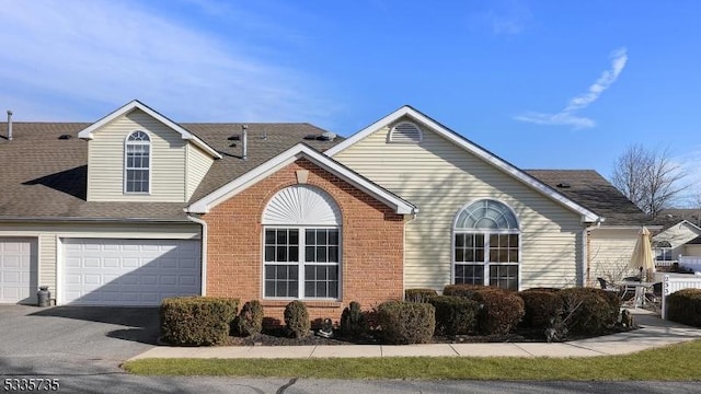 view of property exterior featuring an attached garage, roof with shingles, aphalt driveway, and brick siding