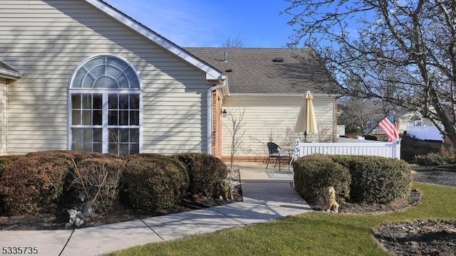 view of home's exterior featuring a shingled roof and a patio area