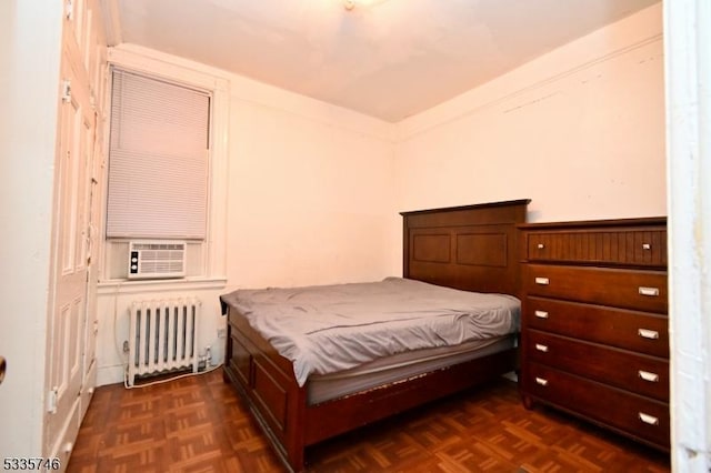 bedroom with dark parquet flooring, radiator, and cooling unit