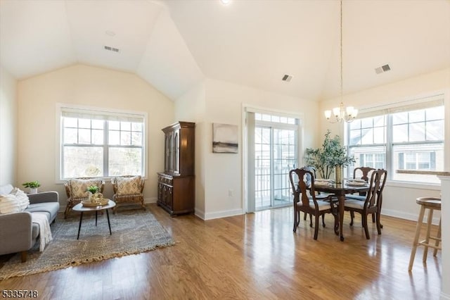 dining room featuring light wood-type flooring, lofted ceiling, and visible vents