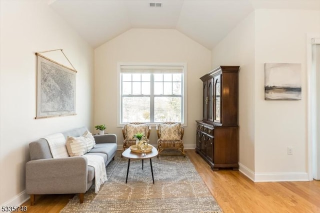 living area with visible vents, vaulted ceiling, light wood-style flooring, and baseboards