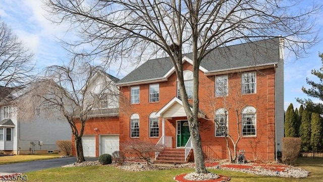 colonial-style house featuring a garage, driveway, and brick siding