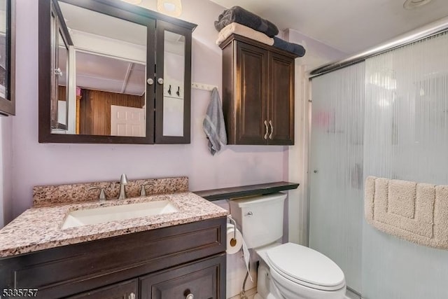 bathroom featuring vanity, a shower with door, and toilet