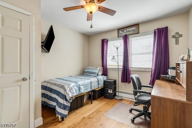 bedroom featuring ceiling fan, a baseboard heating unit, and light wood-type flooring