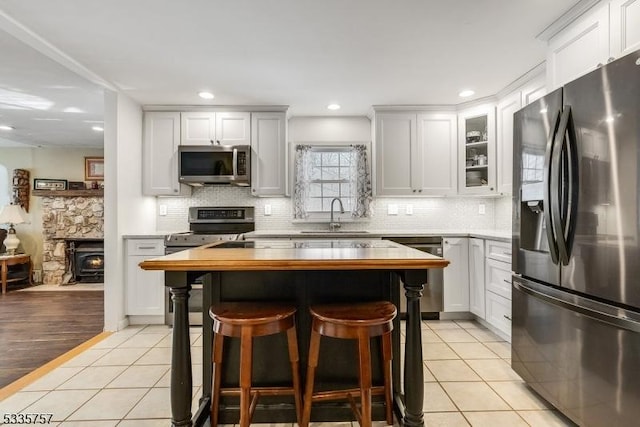 kitchen featuring stainless steel appliances, a kitchen breakfast bar, wooden counters, and light tile patterned floors