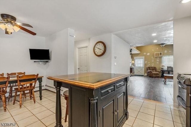 kitchen featuring stainless steel electric range oven, a kitchen breakfast bar, a center island, light tile patterned floors, and ceiling fan