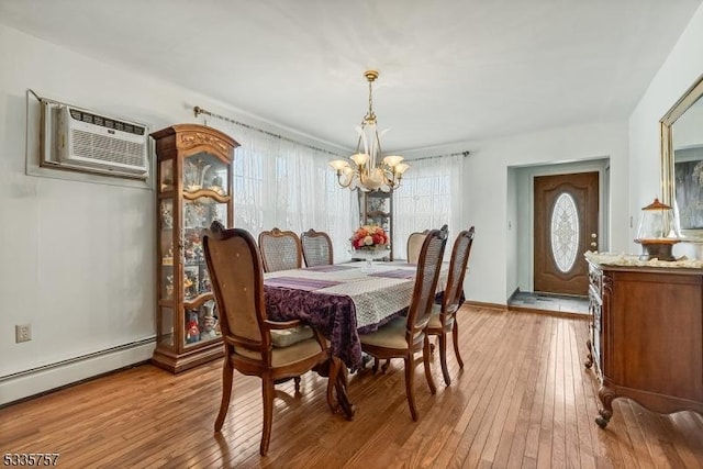 dining area with a baseboard radiator, an AC wall unit, a chandelier, and light wood-type flooring