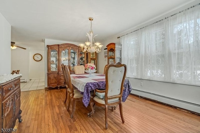 dining area featuring ceiling fan with notable chandelier, baseboard heating, and light hardwood / wood-style flooring