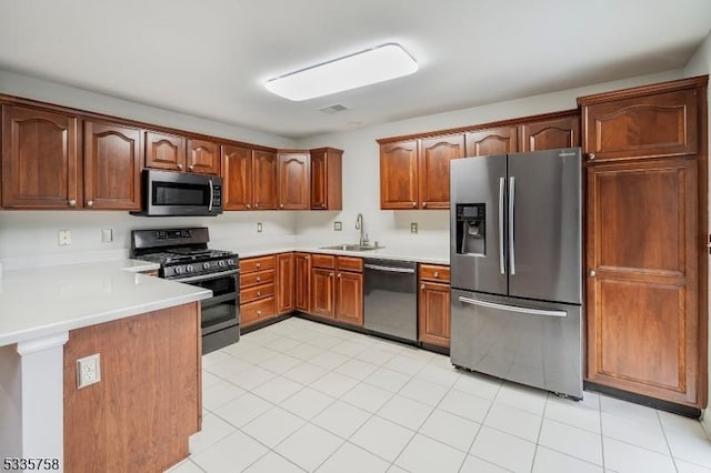 kitchen featuring sink, light tile patterned flooring, kitchen peninsula, and appliances with stainless steel finishes