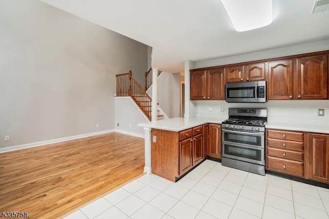 kitchen featuring stainless steel appliances, kitchen peninsula, and light hardwood / wood-style flooring