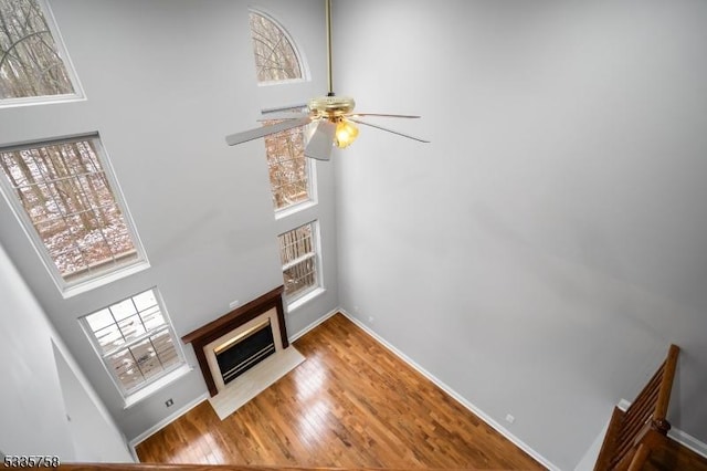 living room featuring hardwood / wood-style flooring, a towering ceiling, and ceiling fan