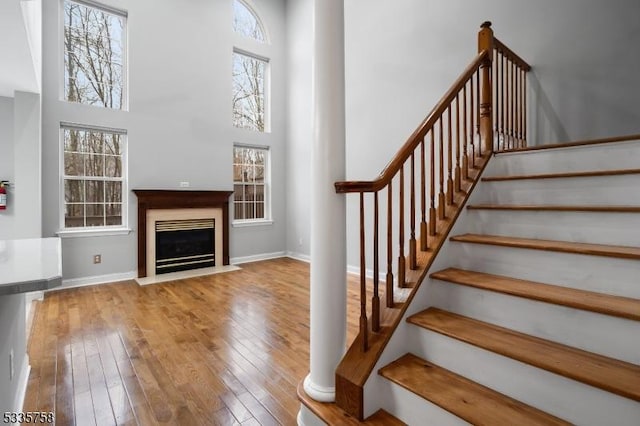 stairs with hardwood / wood-style floors and a high ceiling