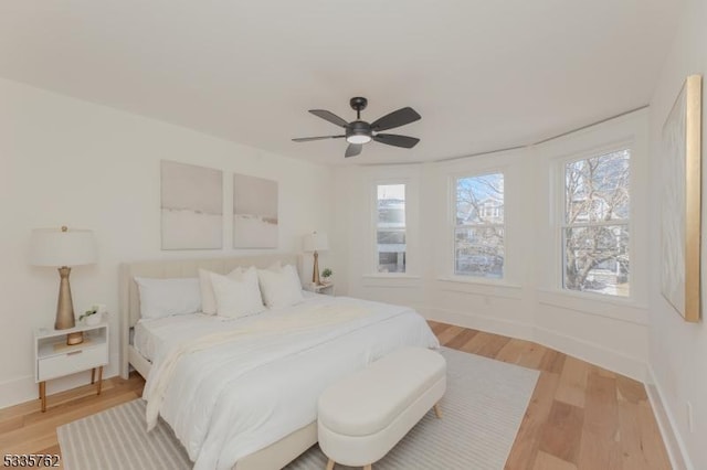 bedroom featuring light wood-style flooring, baseboards, and ceiling fan