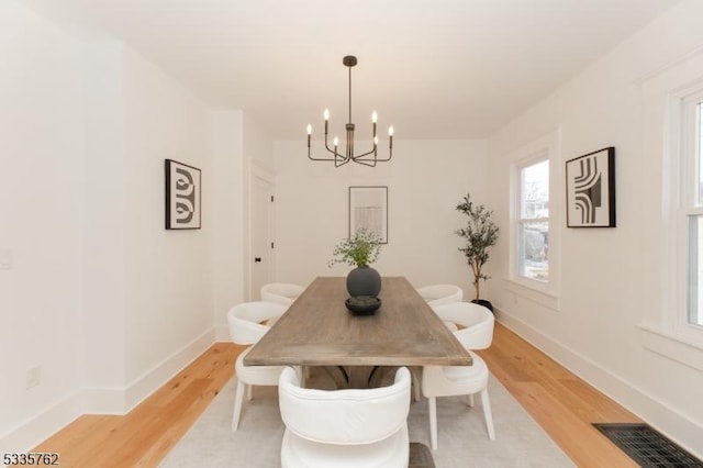 dining room with light wood-style floors, visible vents, a notable chandelier, and baseboards