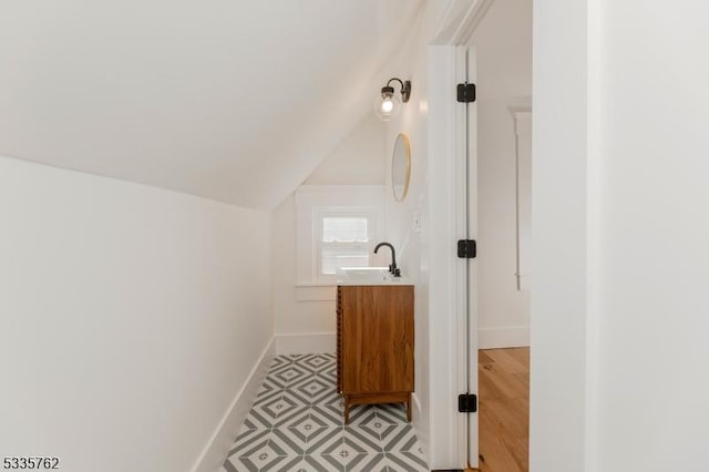 bathroom featuring lofted ceiling, vanity, and baseboards