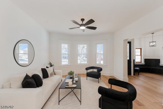 living room with ceiling fan, light wood finished floors, and baseboards