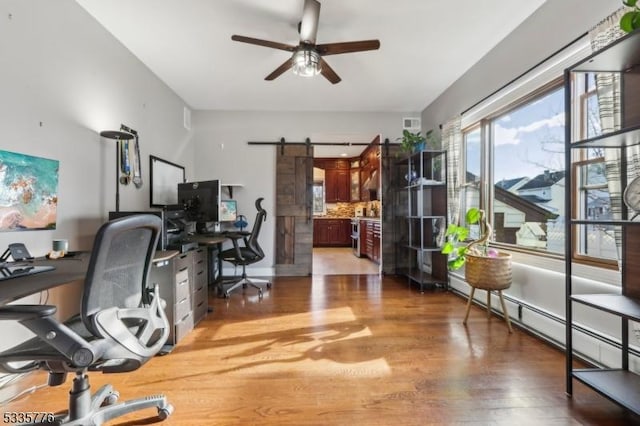 office featuring ceiling fan, a barn door, hardwood / wood-style floors, and a baseboard heating unit