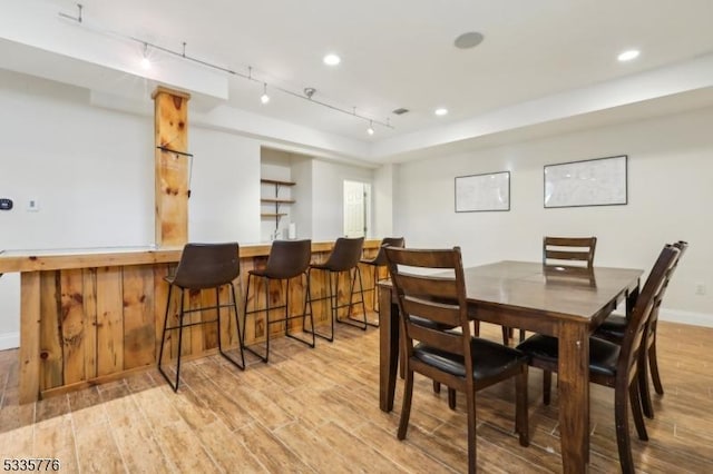 dining area featuring indoor bar, track lighting, and light hardwood / wood-style floors