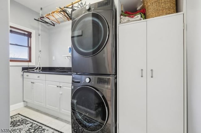 washroom with light tile patterned flooring, cabinets, and stacked washer / drying machine