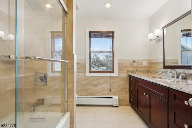 bathroom with tile walls, vanity, tile patterned flooring, and bath / shower combo with glass door