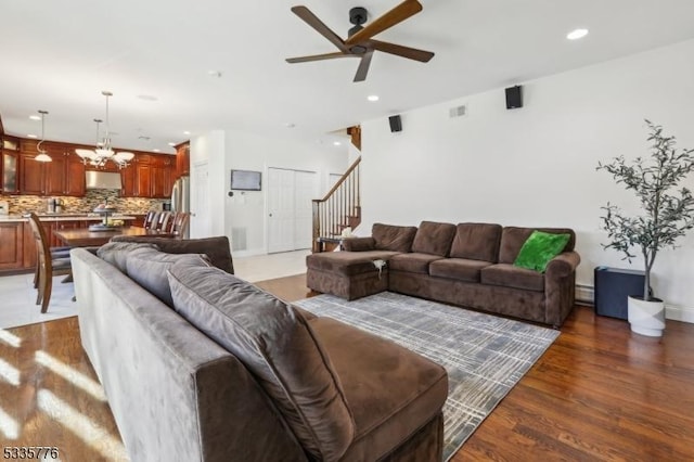 living room with hardwood / wood-style flooring and ceiling fan with notable chandelier