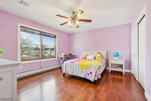 bedroom with hardwood / wood-style flooring, ceiling fan, baseboard heating, and a closet