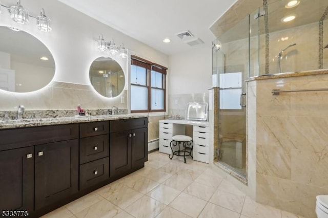 bathroom with vanity, tile walls, an enclosed shower, and baseboard heating