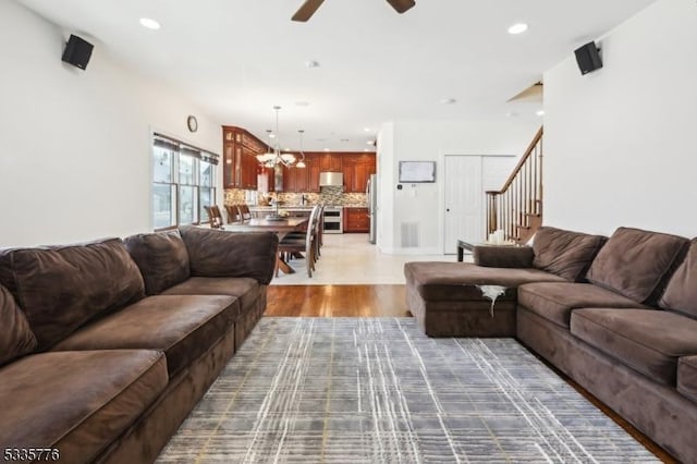 living room with ceiling fan with notable chandelier and wood-type flooring