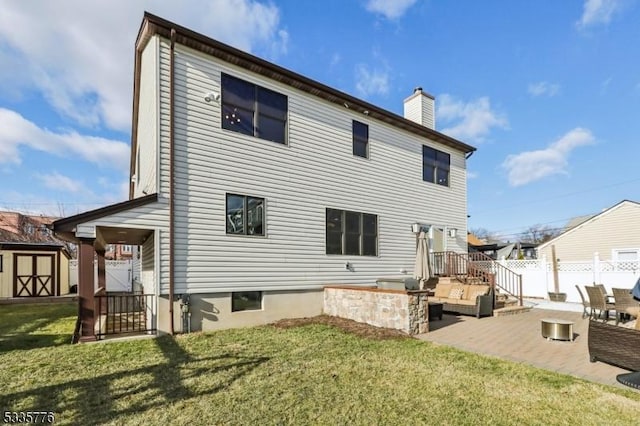 rear view of house featuring an outdoor living space, a shed, a patio, and a lawn