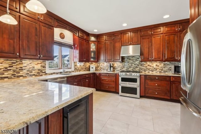 kitchen with sink, appliances with stainless steel finishes, light stone countertops, decorative light fixtures, and beverage cooler