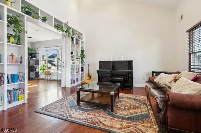 sitting room with a baseboard radiator, a towering ceiling, and dark hardwood / wood-style flooring