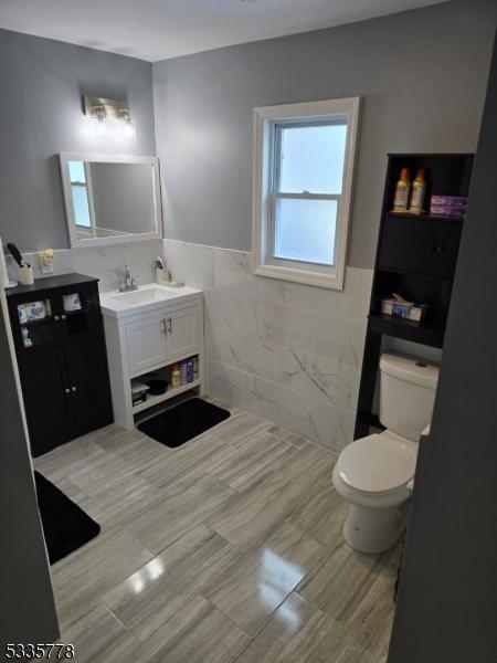 bathroom with vanity, tile walls, and toilet