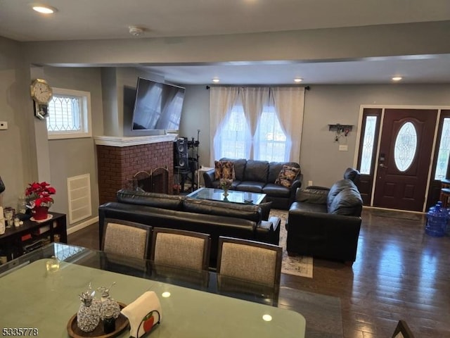 living room with a brick fireplace, beam ceiling, and dark hardwood / wood-style floors