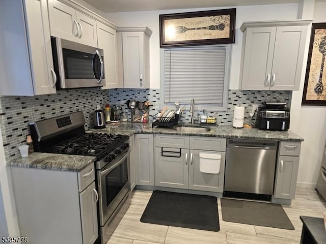 kitchen with backsplash, sink, dark stone counters, and appliances with stainless steel finishes